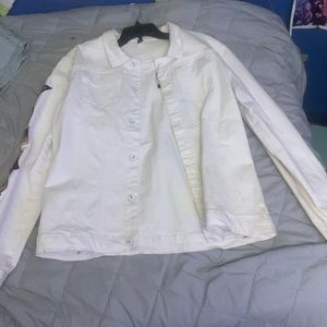 A all white jean jacket with patches on each arm sleeve